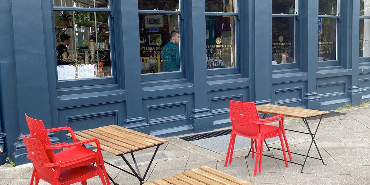 Side view of the Terra Nova cafe with red chairs and wooden tables outside